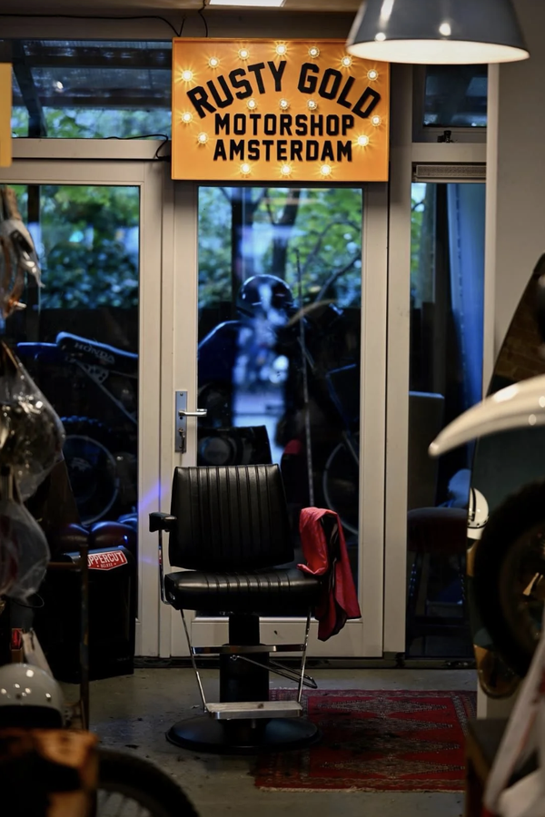 De kappersstoel van Wolf Barbers tussen de motorkleding en helmen in Rusty Gold